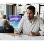 Gestor avaliando “CURRÍCULO” no celular dentro de um restaurante, ilustrando como contratar temporários para restaurante de forma rápida e organizada.